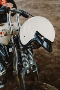 Close-up of a vintage motorcycle featuring a white helmet hanging on the handlebars.