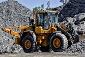 Powerful yellow construction loader moving gravel in an industrial quarry site.